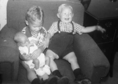 Three-year-old Kent holding one-month old me, sitting with 18 month old Brad in our house in Newton Highlands, Mass.